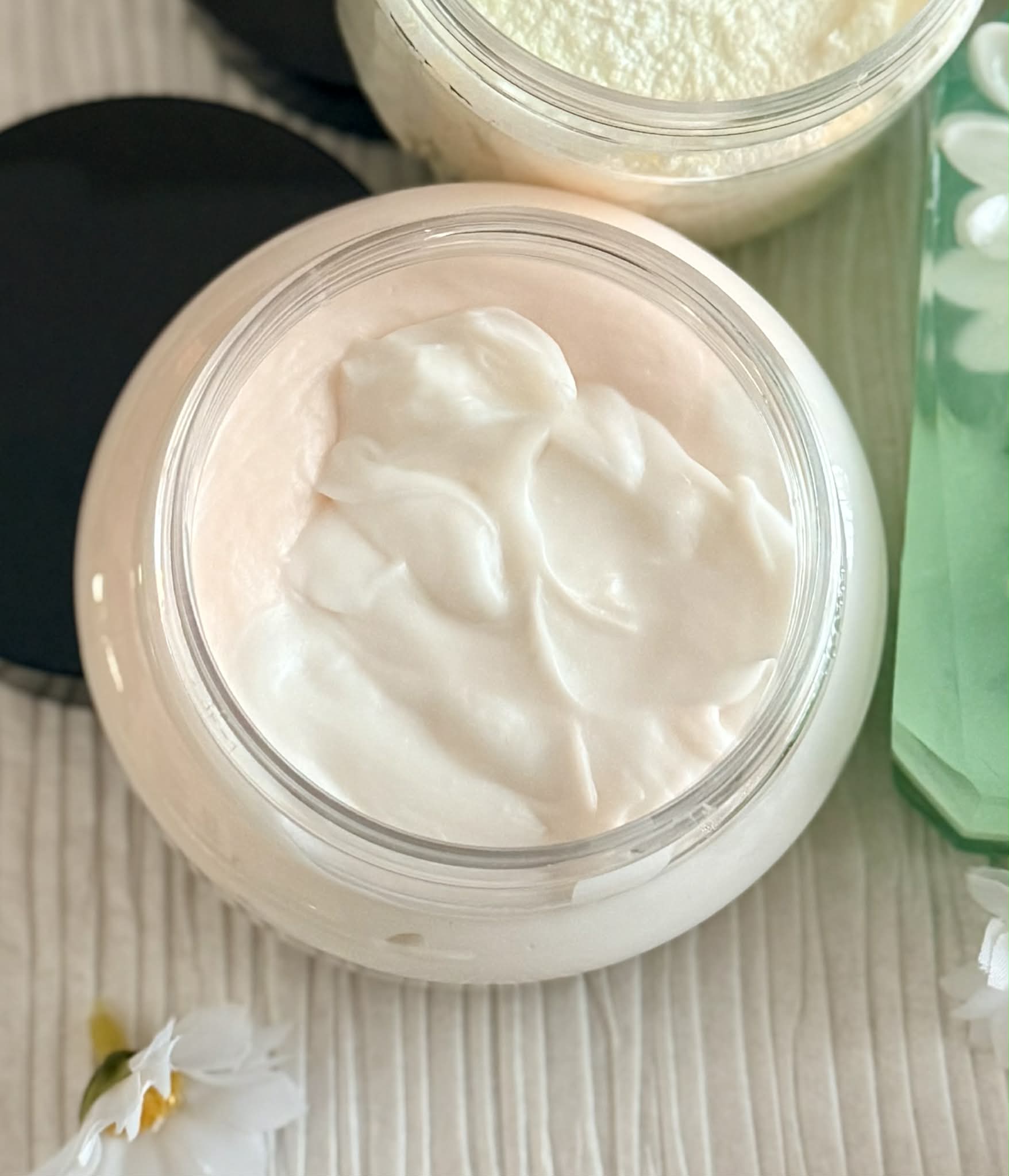 Jar of white lotion on textured background and flower
