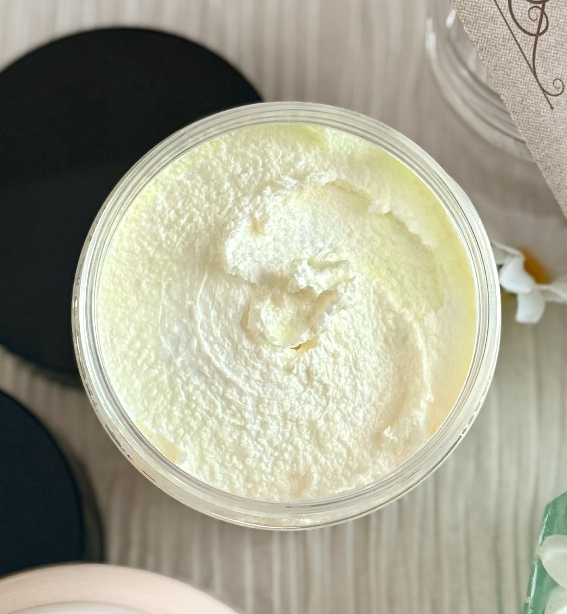 Jar of white sugar scrub with a floral pattern on a textured surface