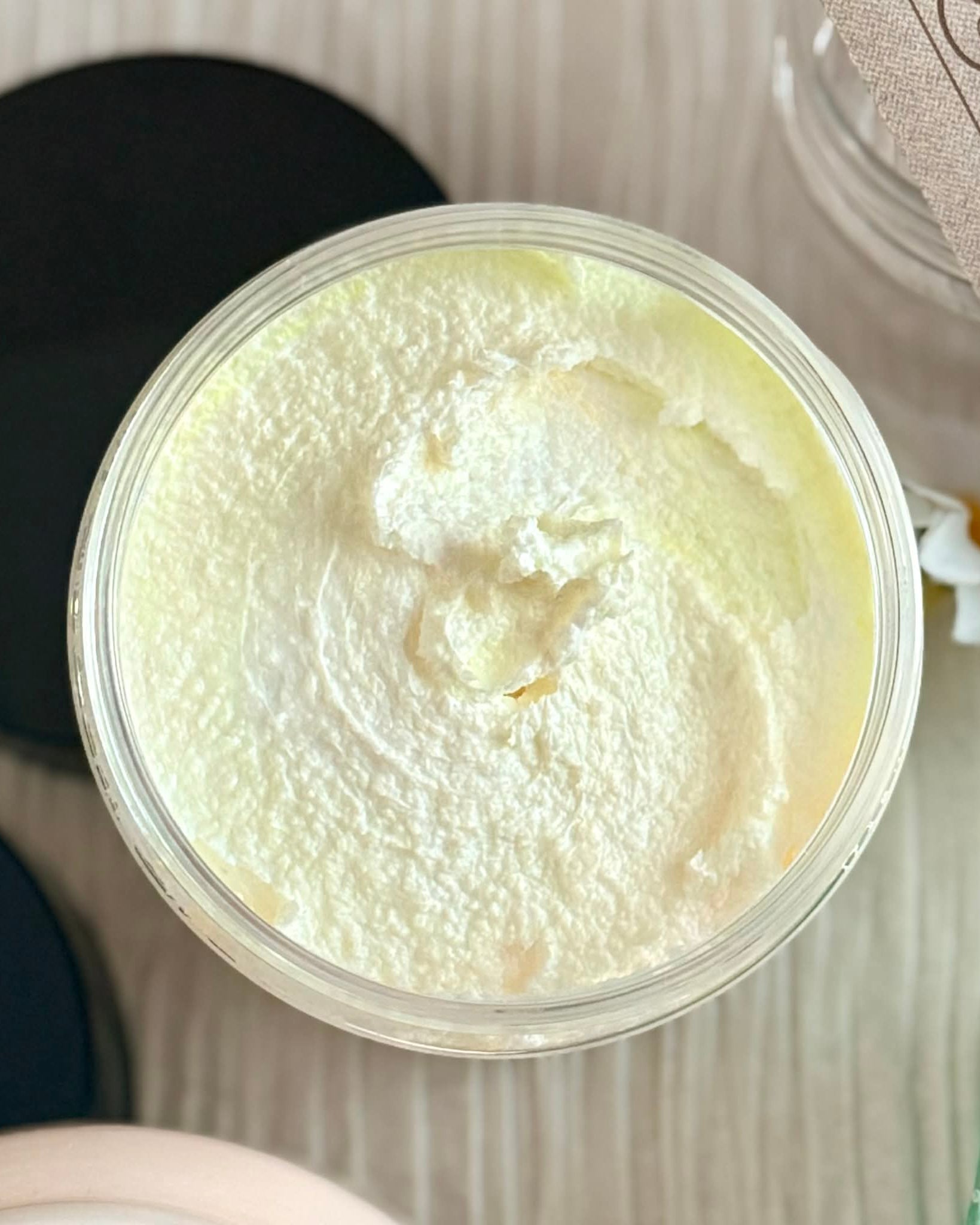 Jar of pale yellow sugar scrub on a textured background
